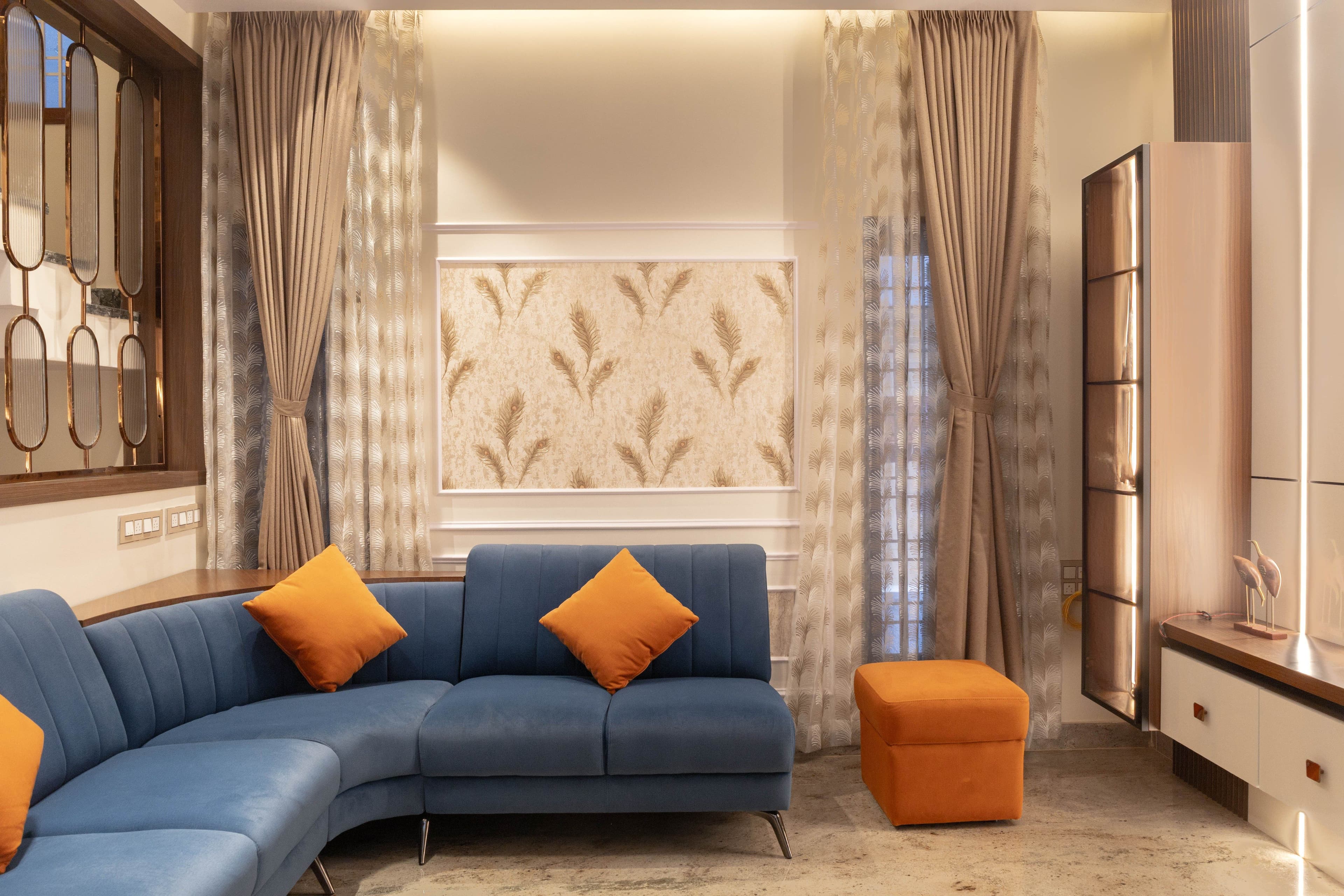 Living room — blue sectional sofa, orange ottoman and floor-to-ceiling curtains